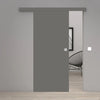 A modern sliding door in a matte gray finish, shown partially open in a minimalist gray interior room with light wood flooring and a black wire chair visible in the background.