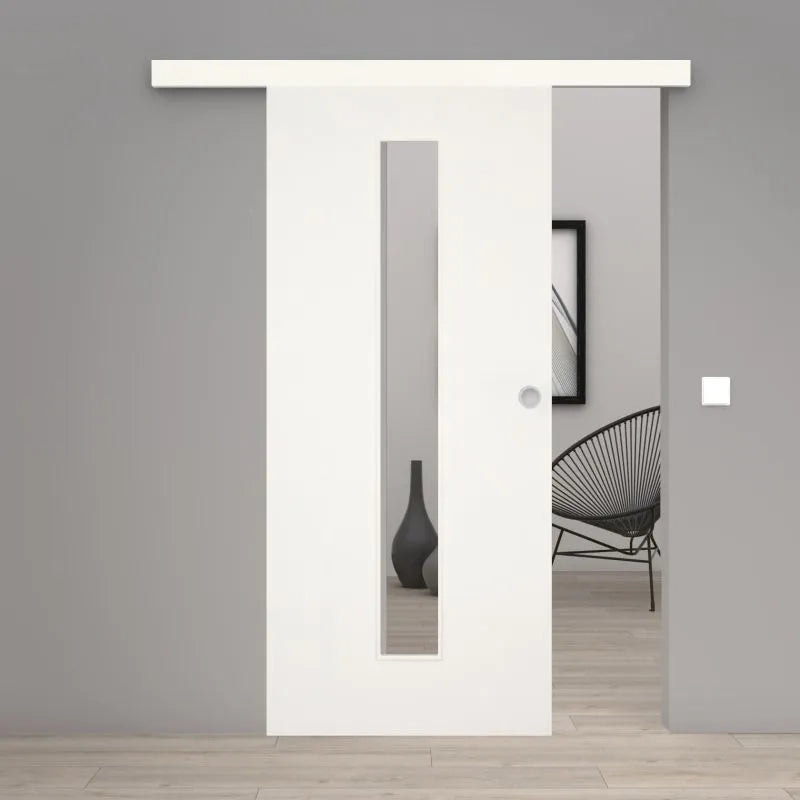 A modern white sliding door with a vertical rectangular glass panel, shown installed in a minimalist gray interior doorway with light wood flooring and a black wire chair visible in the background.