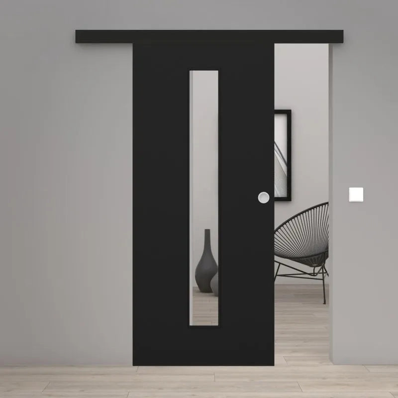 A modern black sliding door with a vertical rectangular glass panel, shown partially open in a minimalist interior setting with light gray walls and light wood flooring.