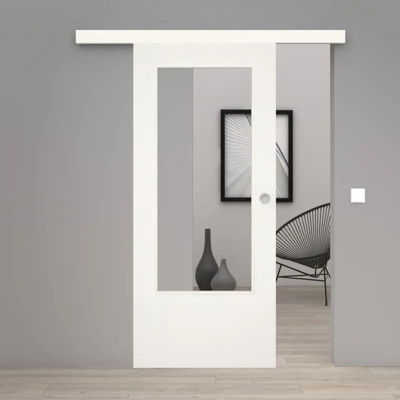 A modern white sliding door with a large rectangular glass panel, shown installed in a minimalist gray interior room with light wood flooring and a black wire chair.