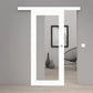 A modern white sliding door frame installed in a minimalist gray interior room with light wood flooring, a black wire chair, and a framed black-and-white wall art piece.